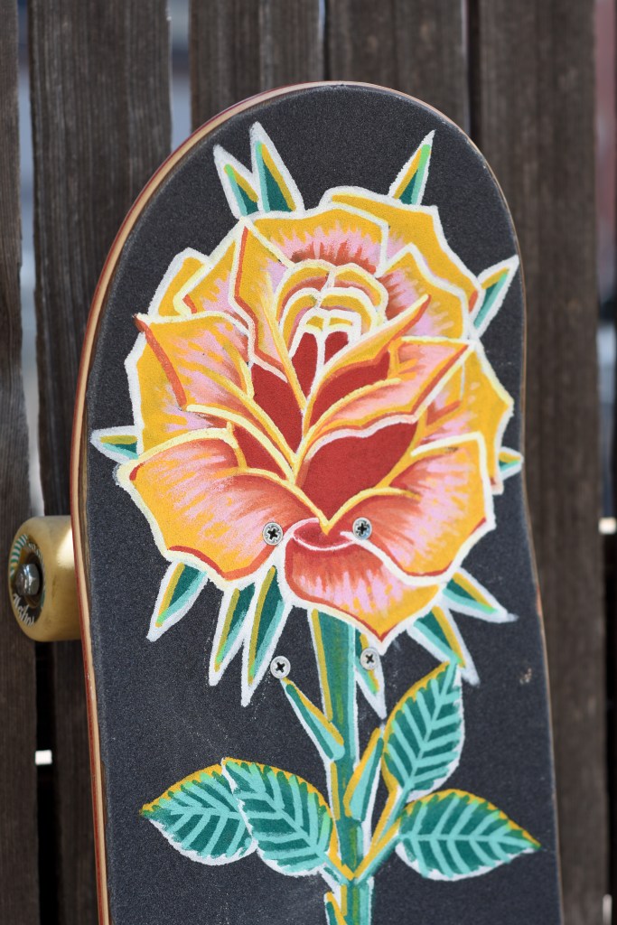 Griptape painting on skateboard depicting a pink and yellow rose